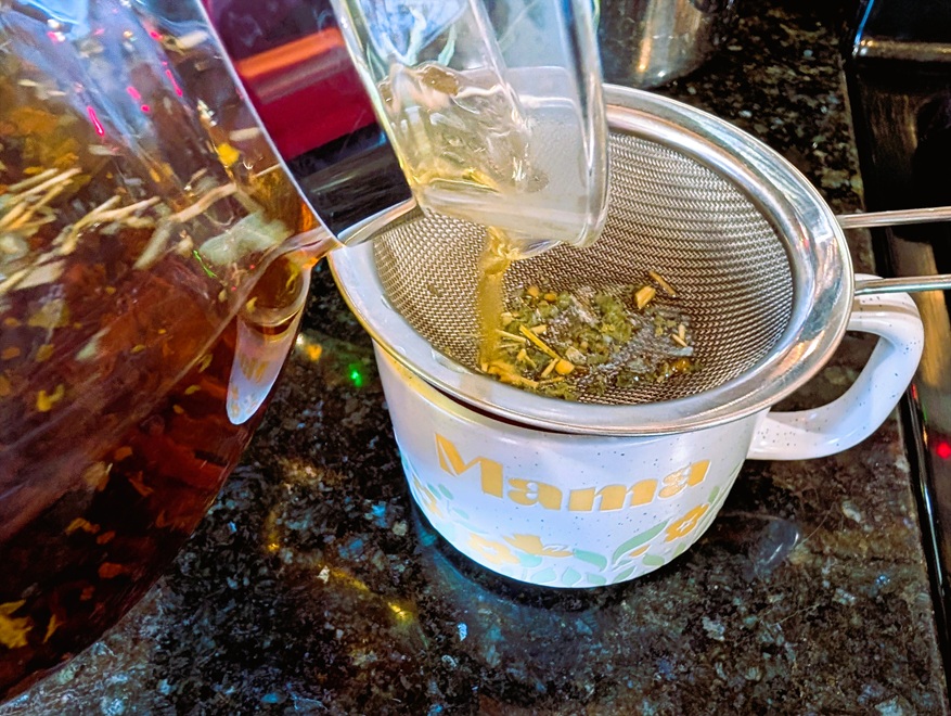 Straining loose leaf red raspberry tea into a mug.